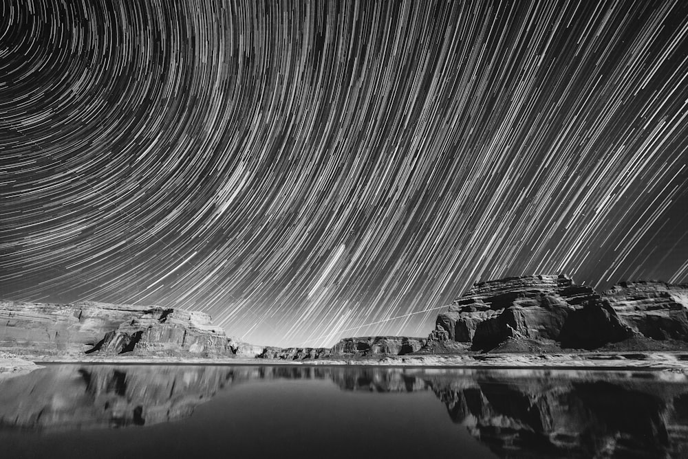 Graustufenfotografie eines ruhigen Gewässers unter dem Himmel