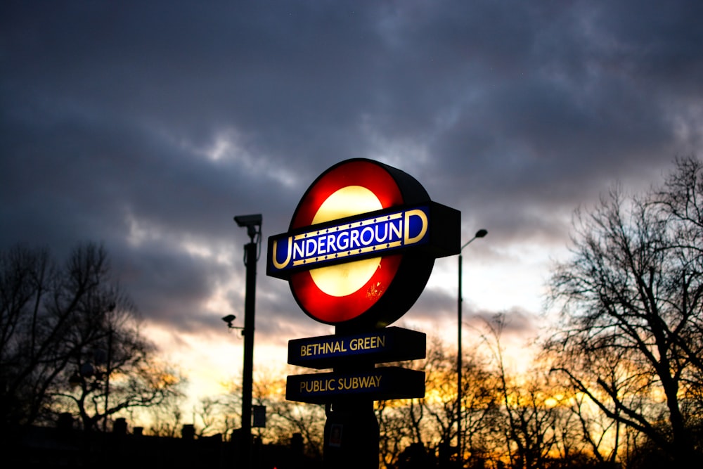 gelb und rot beleuchtete U-Bahn-Beschilderung unter grauem, bewölktem Himmel