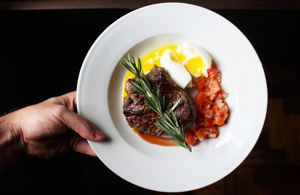 personne tenant une assiette en céramique blanche