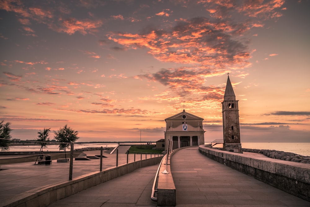 Pontile di legno marrone vicino all'edificio in cemento marrone durante il tramonto