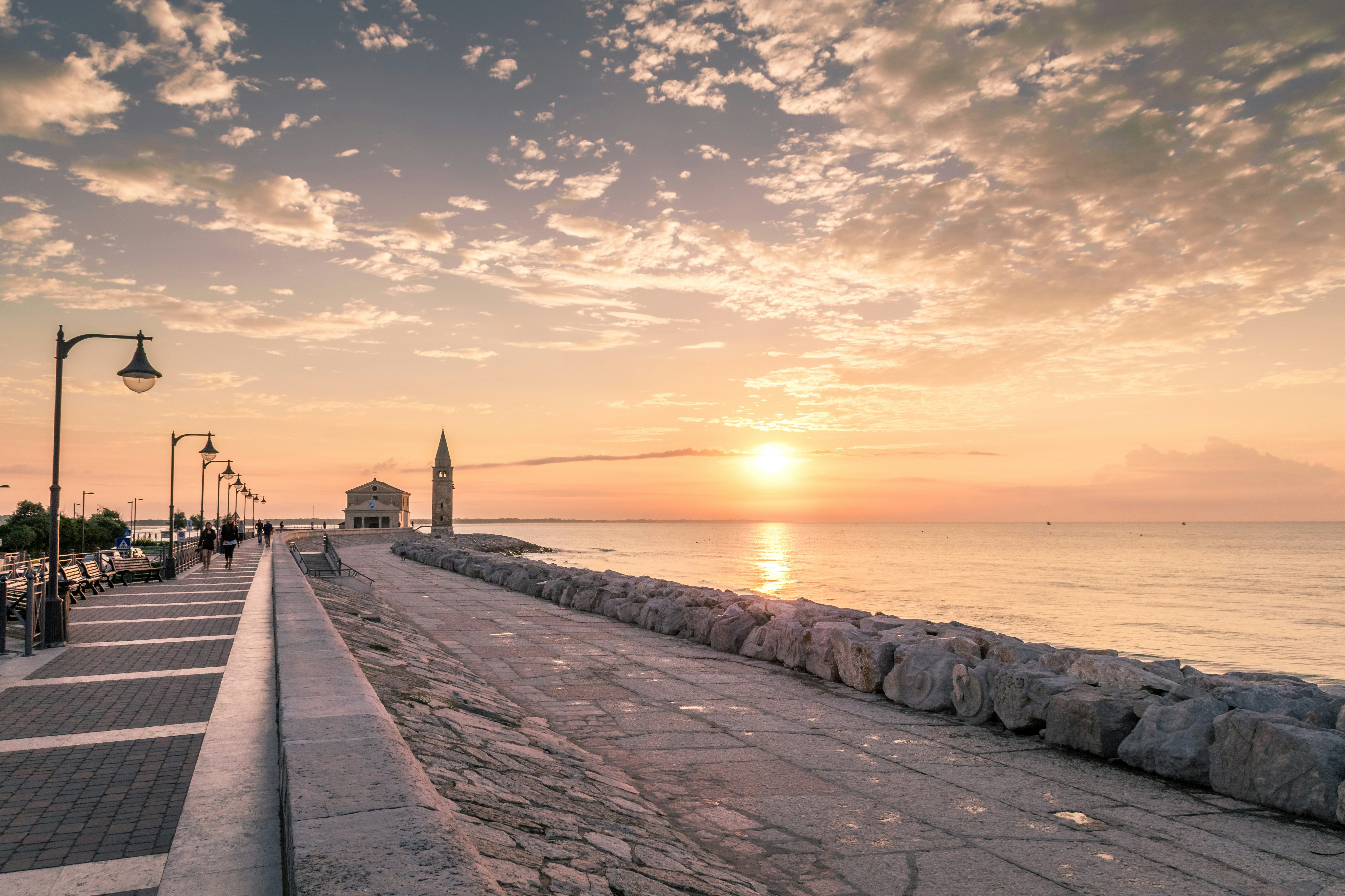 people walking on concrete dock during sunset
