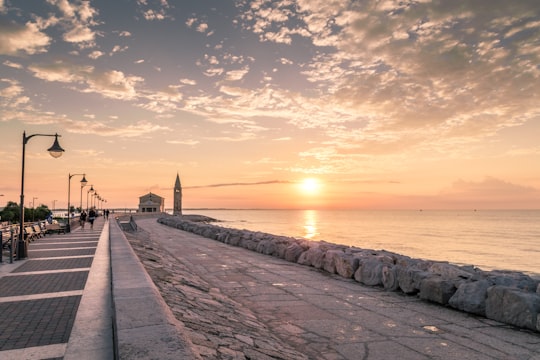 people walking on concrete dock during sunset in Caorle Italy