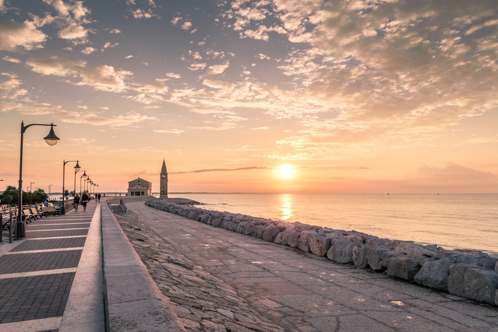 people walking on concrete dock during sunset