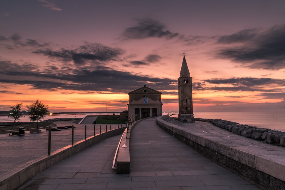 Pontile di legno marrone vicino all'edificio in cemento marrone durante il tramonto