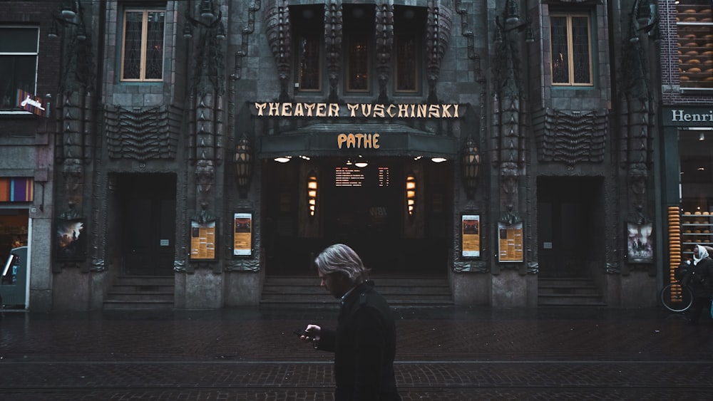 homem em pé perto do edifício do Teatro Tuschinski