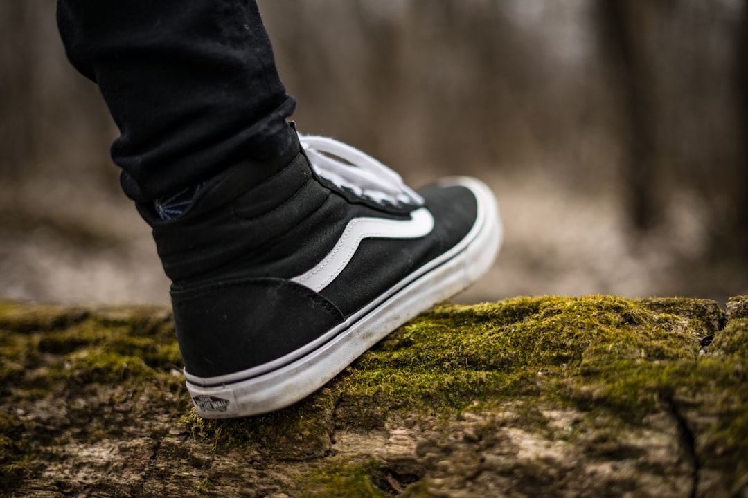 person wearing black and white Vans Sk8-Hi,