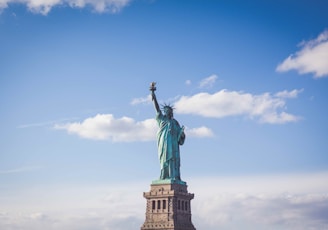 Statue of Liberty, New York under white and blue cloudy skies