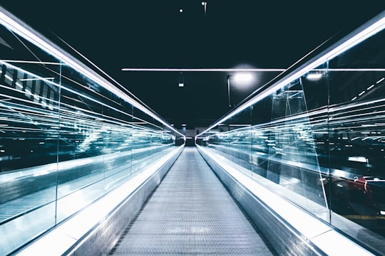 gray conveyor between glass frames at nighttime in Łódź Fabryczna railway Station Poland