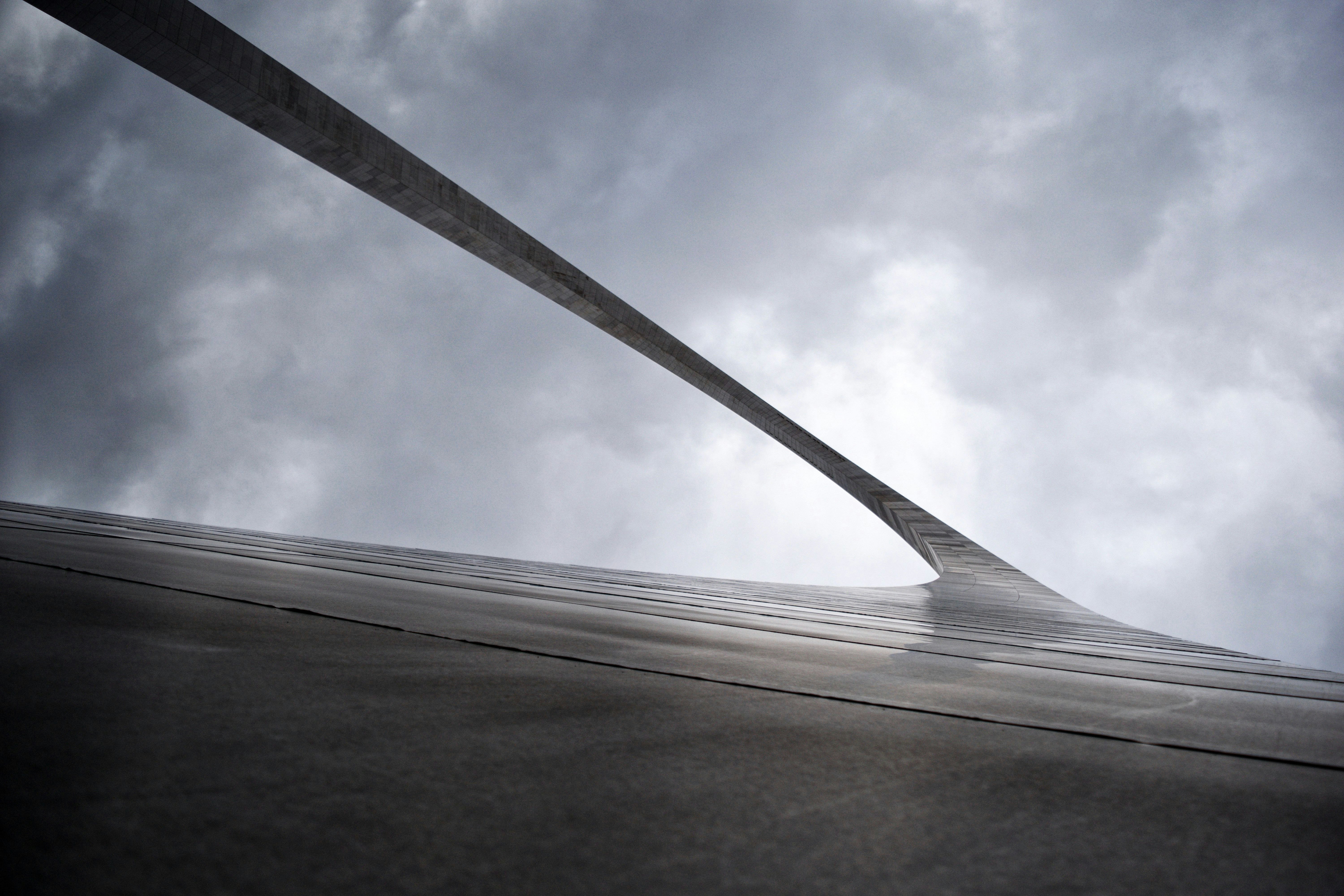greyscale low-angle photography of arc gate under cloudy sky