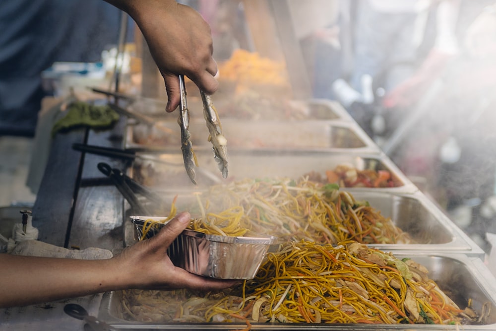 A cook putting Asian noodles into a take-out box