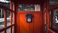 black rotary telephone mounted on red wooden wall