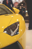 Close-up of a sleek sports car's headlight shining under event lights.
