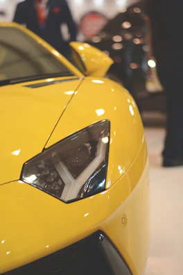 Close-up of a sleek sports car's headlight shining under event lights.