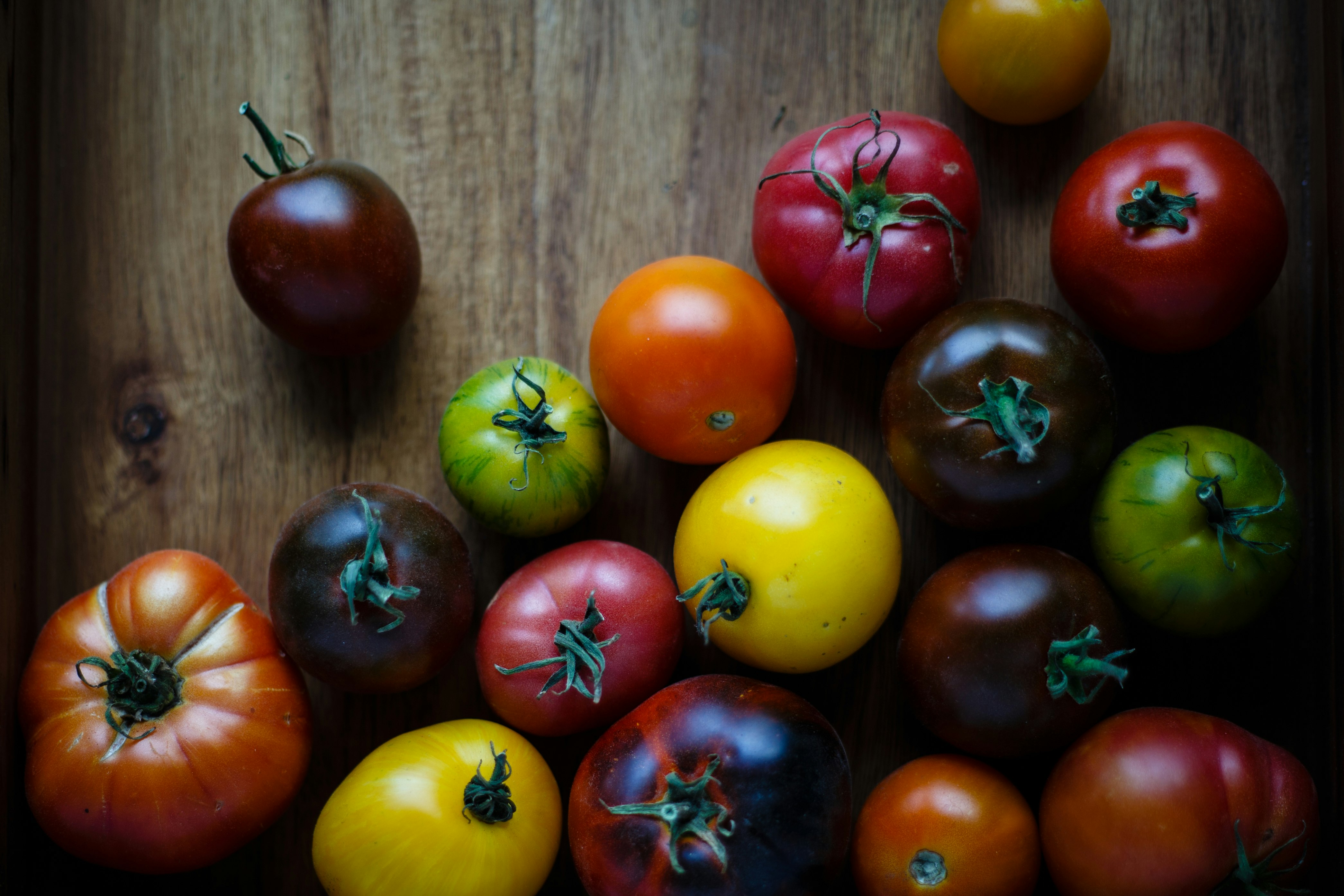 tomatoes of different colors displayed on a wooden table