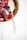 A bowl of granola topped with a mixture of fresh and frozen berries, including raspberries, blueberries, and strawberries, with a dollop of yogurt. A spoon is placed inside the bowl, and the light cream color of the bowl contrasts with the vibrant red and purple of the berries.
