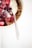 A bowl of granola topped with a mixture of fresh and frozen berries, including raspberries, blueberries, and strawberries, with a dollop of yogurt. A spoon is placed inside the bowl, and the light cream color of the bowl contrasts with the vibrant red and purple of the berries.