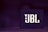 A box-shaped object with the letters JBL prominently displayed in bold, stylish font. The background is blurred and predominantly dark purple, creating a sleek, modern aesthetic.