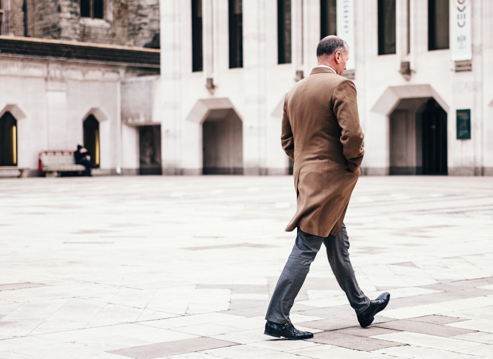 man walking in front of white building