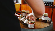 Hands of a mother preparing homemade conserves in Mason jars with vintage kitchen equipment.