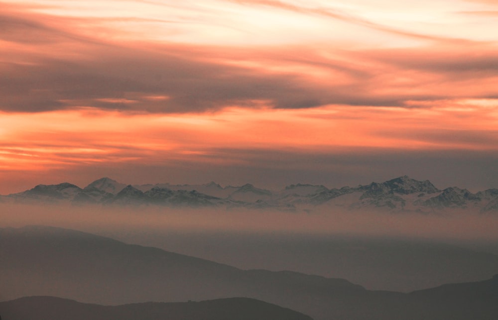 silhouette de montagnes sur un ciel nuageux au coucher du soleil