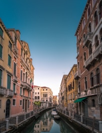 white boat on body of water between buildings