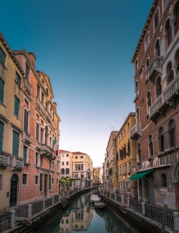 white boat on body of water between buildings