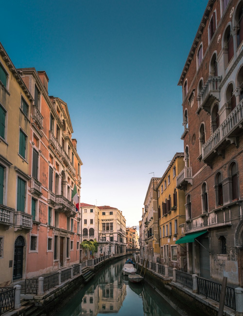 white boat on body of water between buildings