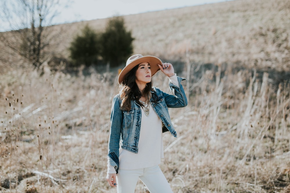 woman holding her hat on grass field