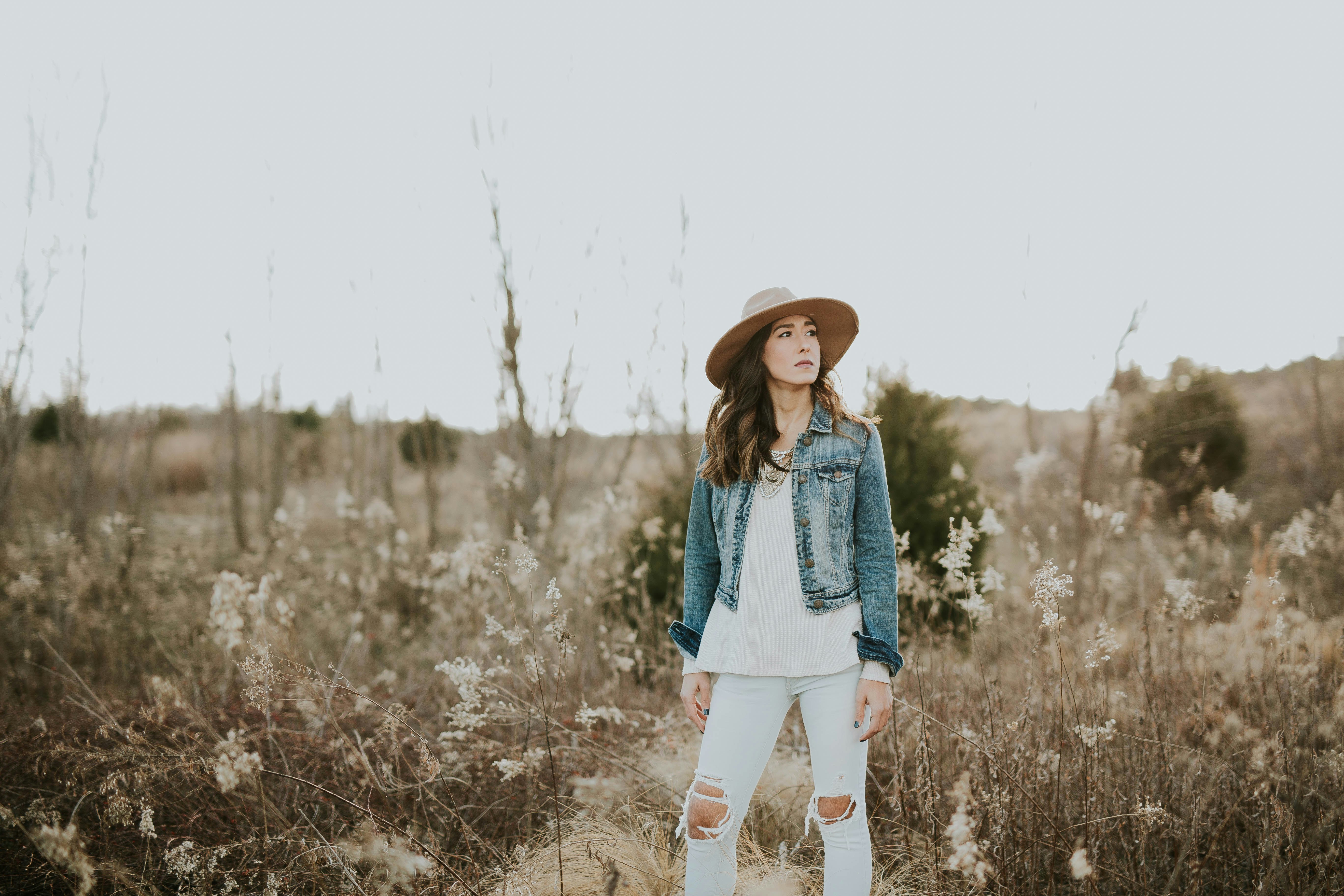 woman in blue denim jacket surrounded by grass during daytime