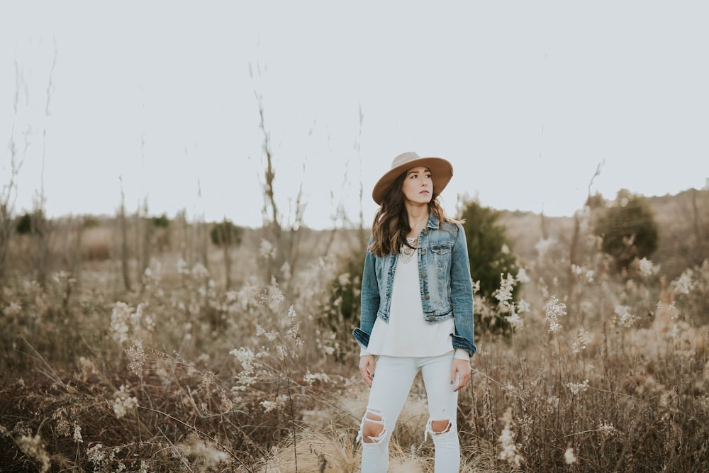 woman in blue denim jacket surrounded by grass during daytime