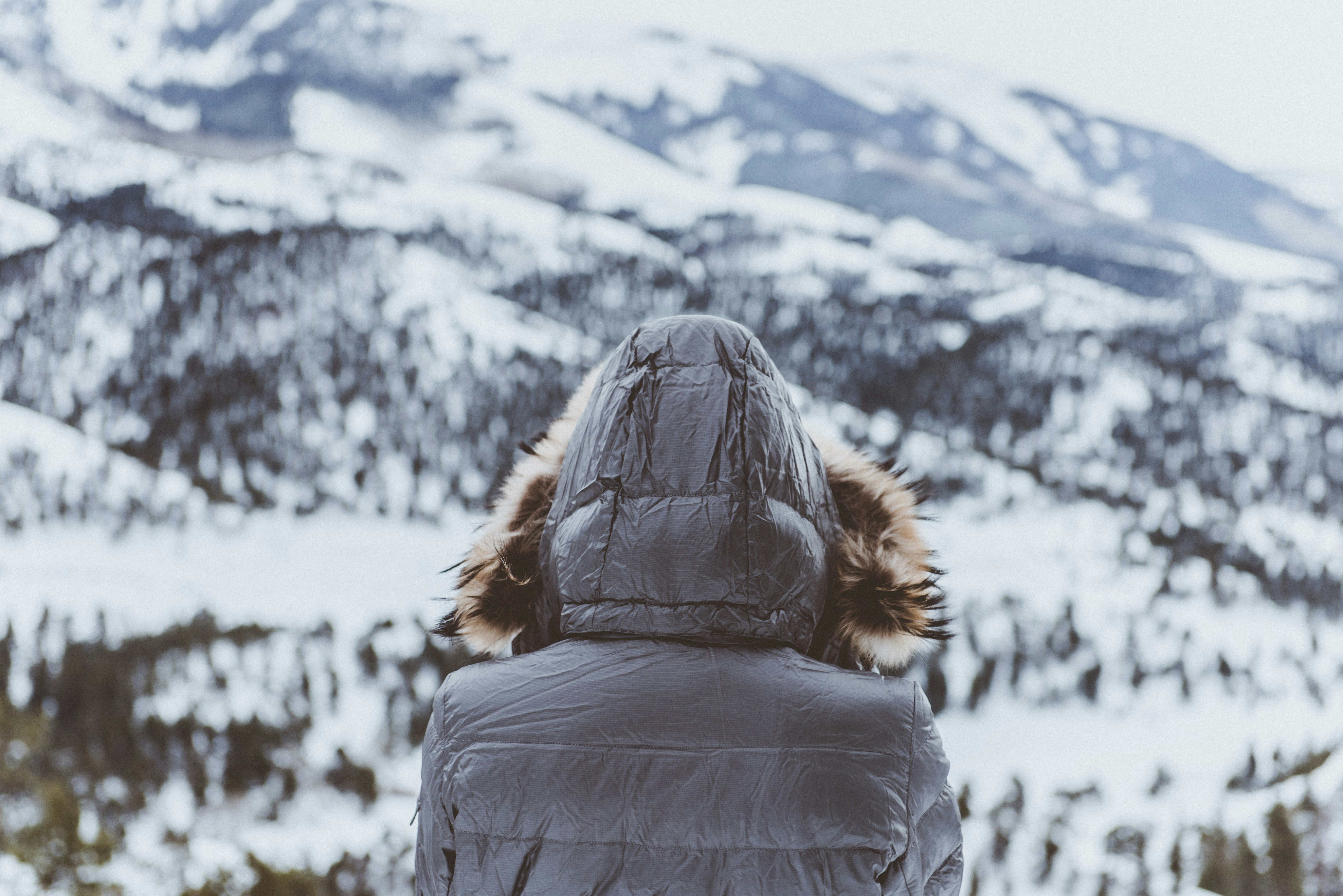 person wearing black parka hoodie in front of mountain