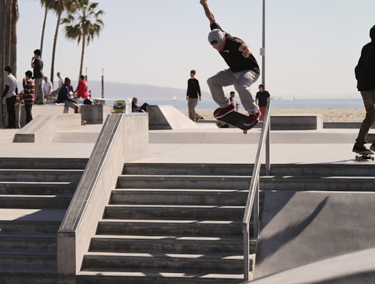 person riding skateboard performing stunt over stairs in Venice United States
