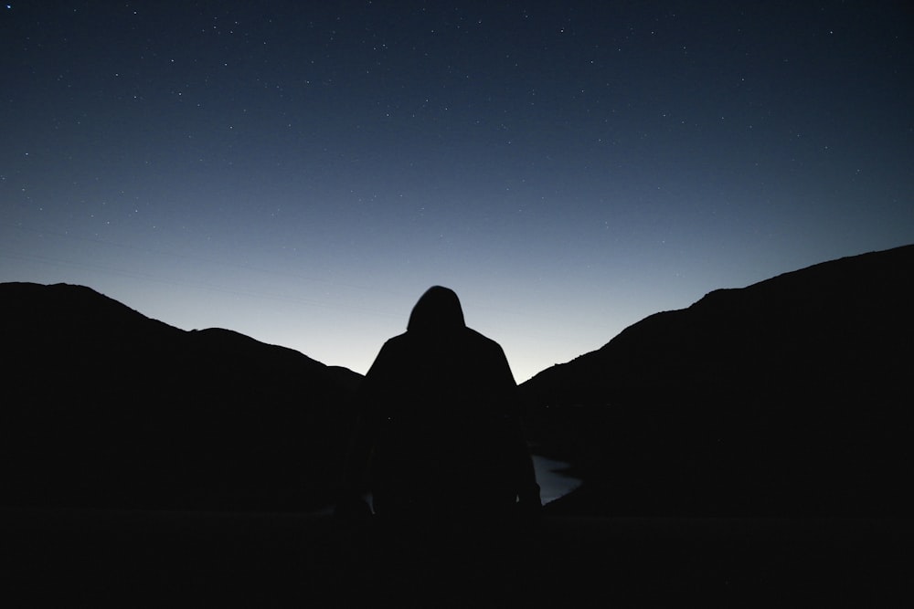 Silhouette einer Person, die dem Sonnenaufgang zugewandt ist