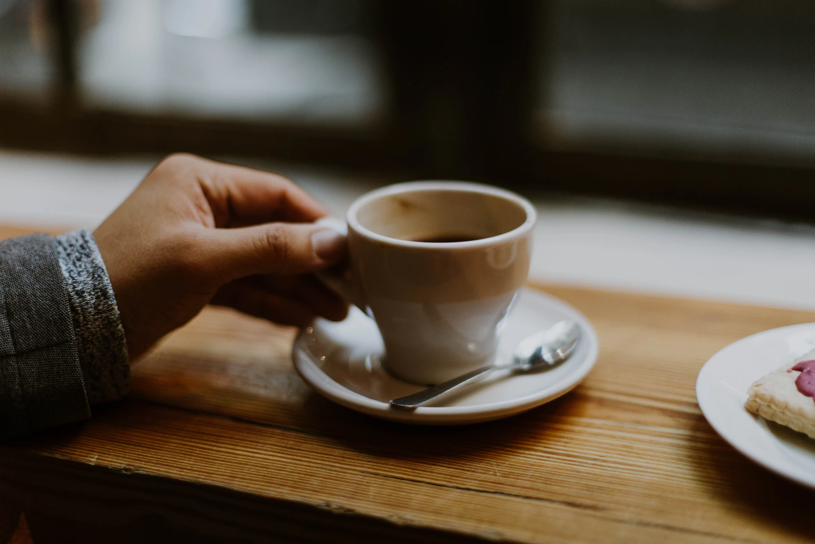 Two hands holding a small white ceramic teacup