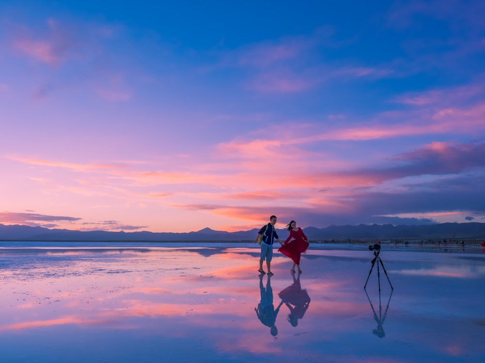 Paar steht am Meeresufer beim Fotografieren während der goldenen Stunde