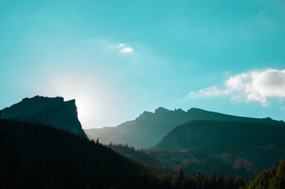 green mountains under white cloudy blue daytime sky bright teams background