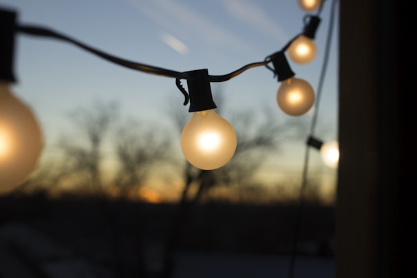 A warm string of battery-powered lights softly illuminating a backyard patio at dusk.