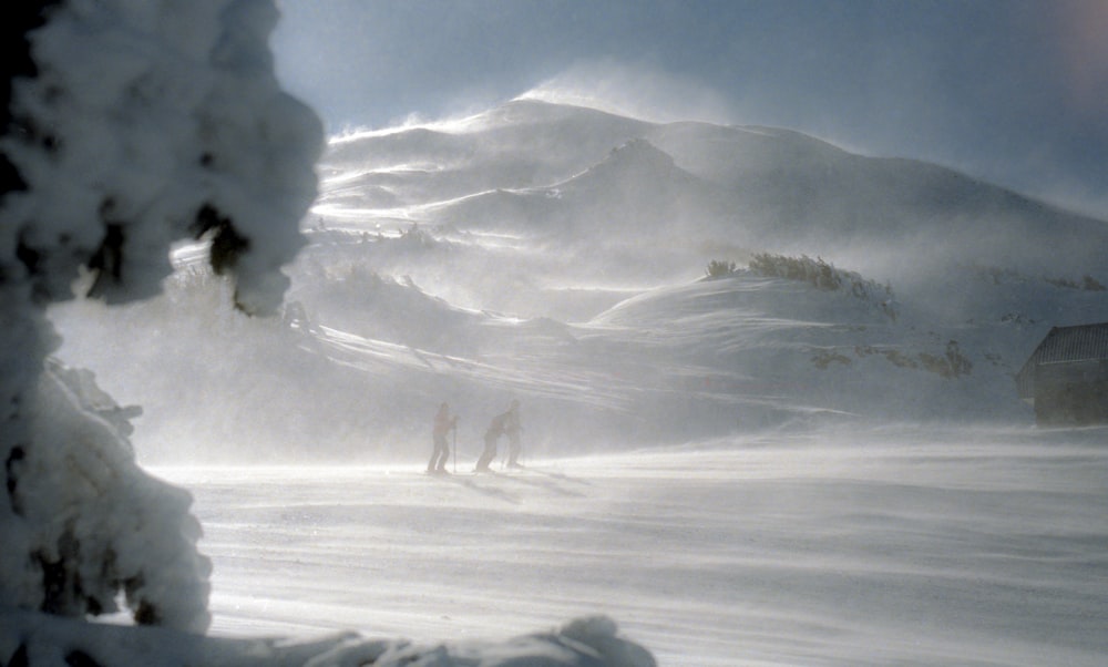 Três homens caminhando na montanha coberta de neve