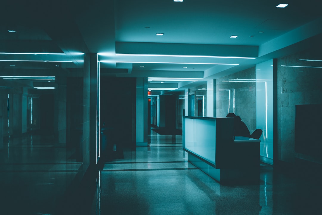 A person sits at a desk in a corridor lit by blue light