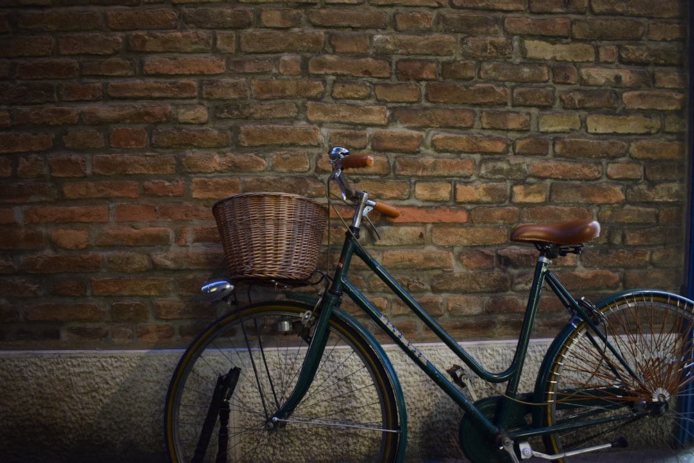 black cruiser bike with basket parked beside wall