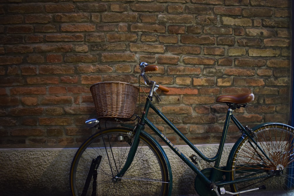 Bicicleta cruiser negra con cesta aparcada junto a la pared
