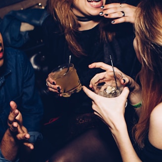 two women talking while holding drinking glasses