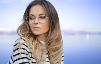 woman wearing black and white striped top and round eyeglasses