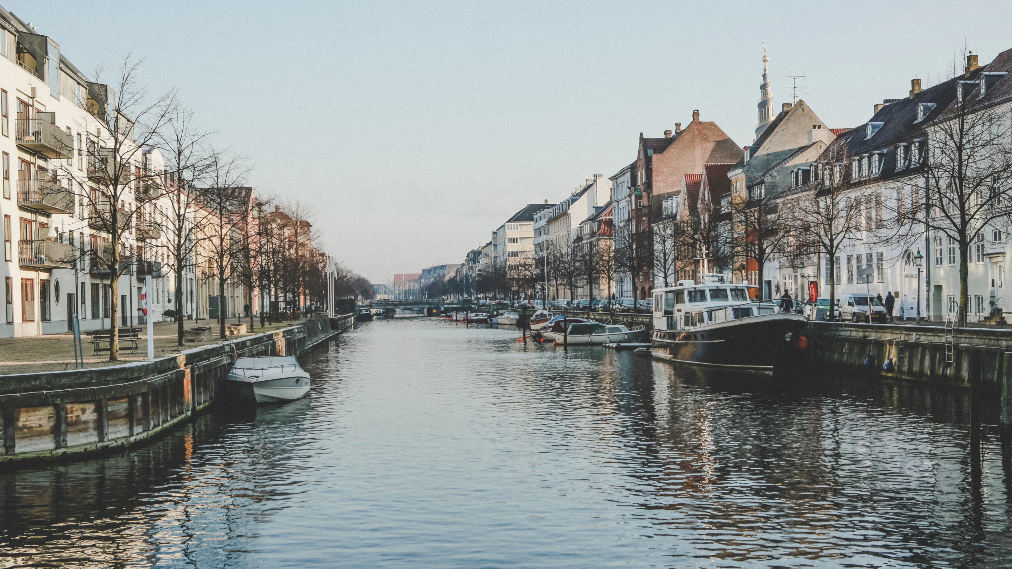 A quiet canal in Copenhagen's Christianshavn lined with townhouses and moored boats under bare winter trees