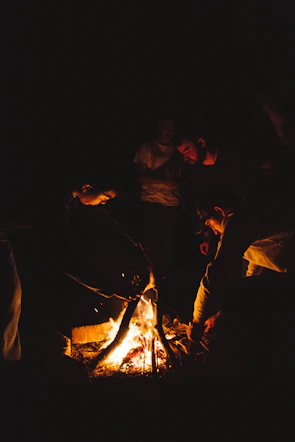 A family gathered around a glowing campfire at dusk, roasting marshmallows.