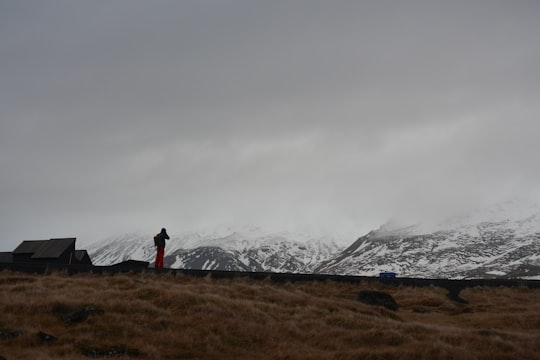 person standing front of mountain in Hellnar Iceland