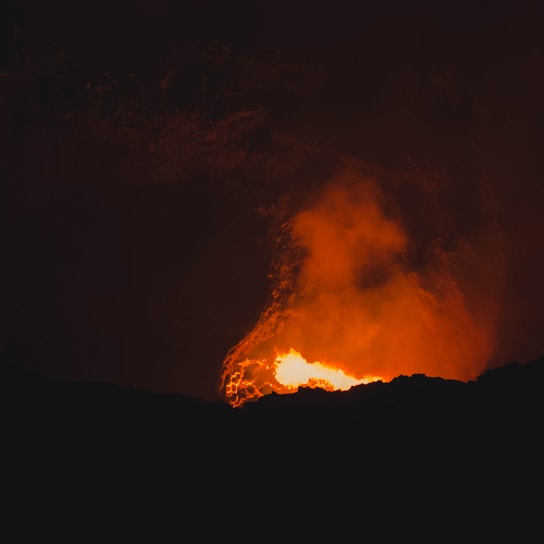 A close-up of flowing molten lava glowing bright orange against a dark background.