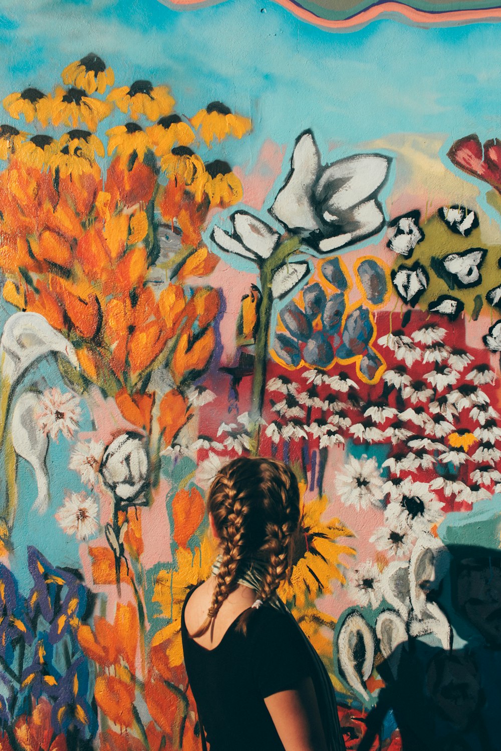 Frau blickt vor floraler Graffiti-Wand
