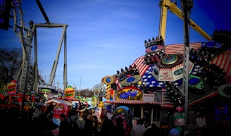 Children enjoying colorful rides and games at a sunny outdoor festival.