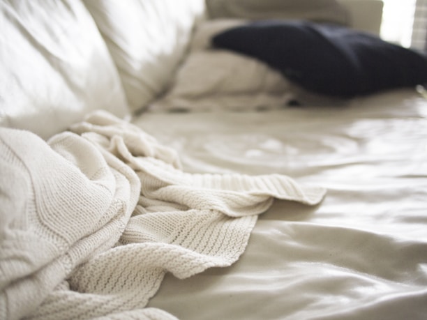 Close-up of a cozy bed dressed in soft, brushed fabric bedding with delicate stitching details.